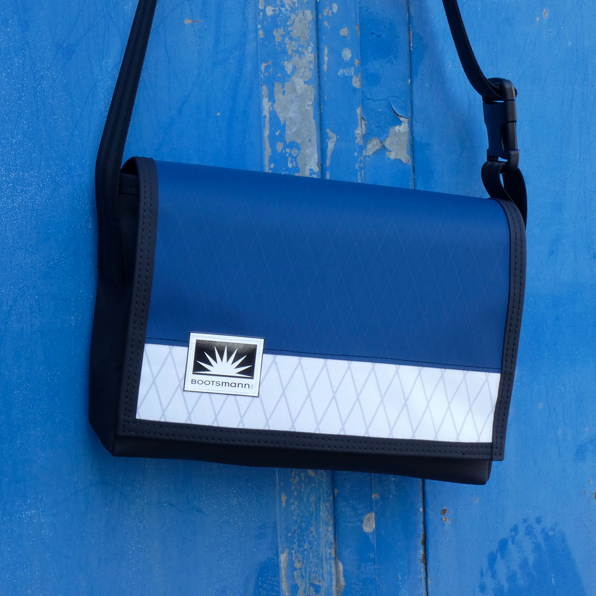 M-Tasche aus X-Pac und Masttaschentuch hängt an rostiger Metalltür