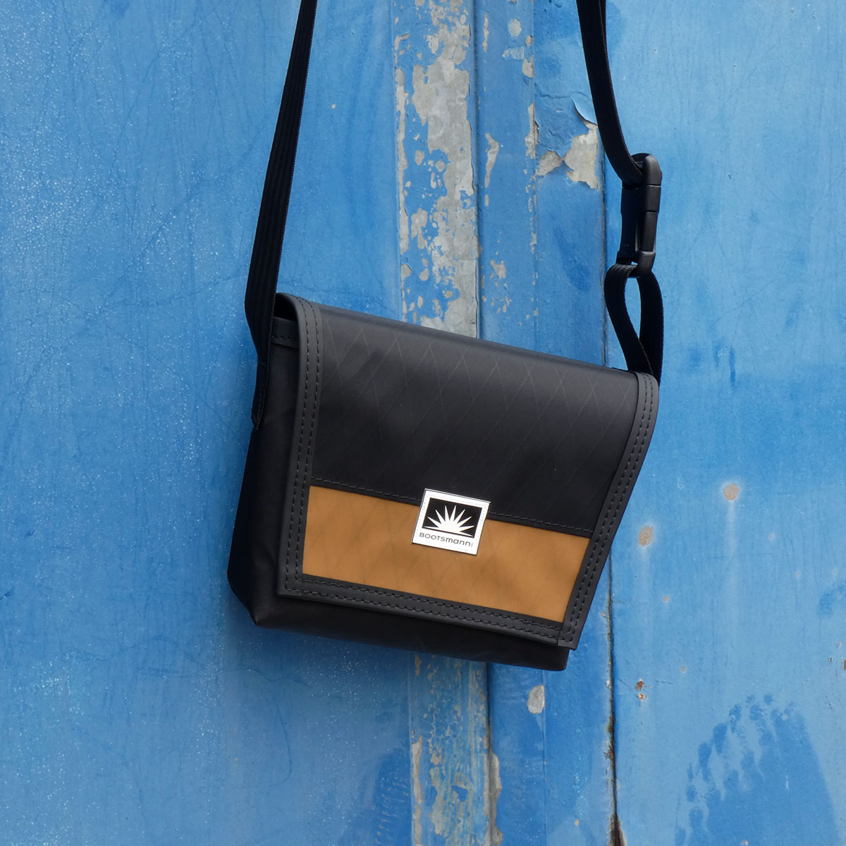 Tasche Bootsmann XS hängt an alter Metalltür – handgefertigte Umhängetasche aus X-PAC und Masttaschentuch, wetterfest und langlebig