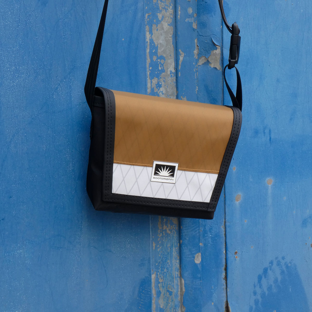 Tasche Bootsmann XS hängt an alter Metalltür – handgefertigte Umhängetasche aus X-PAC und Masttaschentuch, wetterfest und langlebig