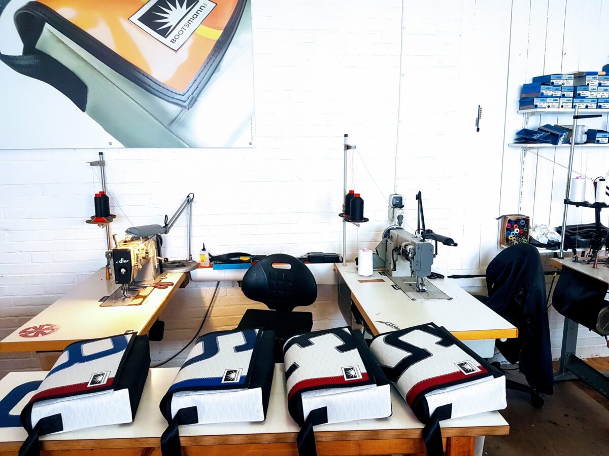 Nähmaschinen auf Werkbänken und halbfertige Taschen aus Segeltuch in der Bootsmann-Manufaktur – Handarbeit trifft maritimes Upcycling
