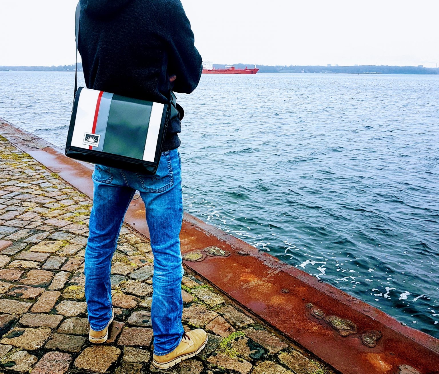 Mann steht am Kai und trägt eine Bootsmann Laptoptasche in 13 Zoll aus LKW-Plane