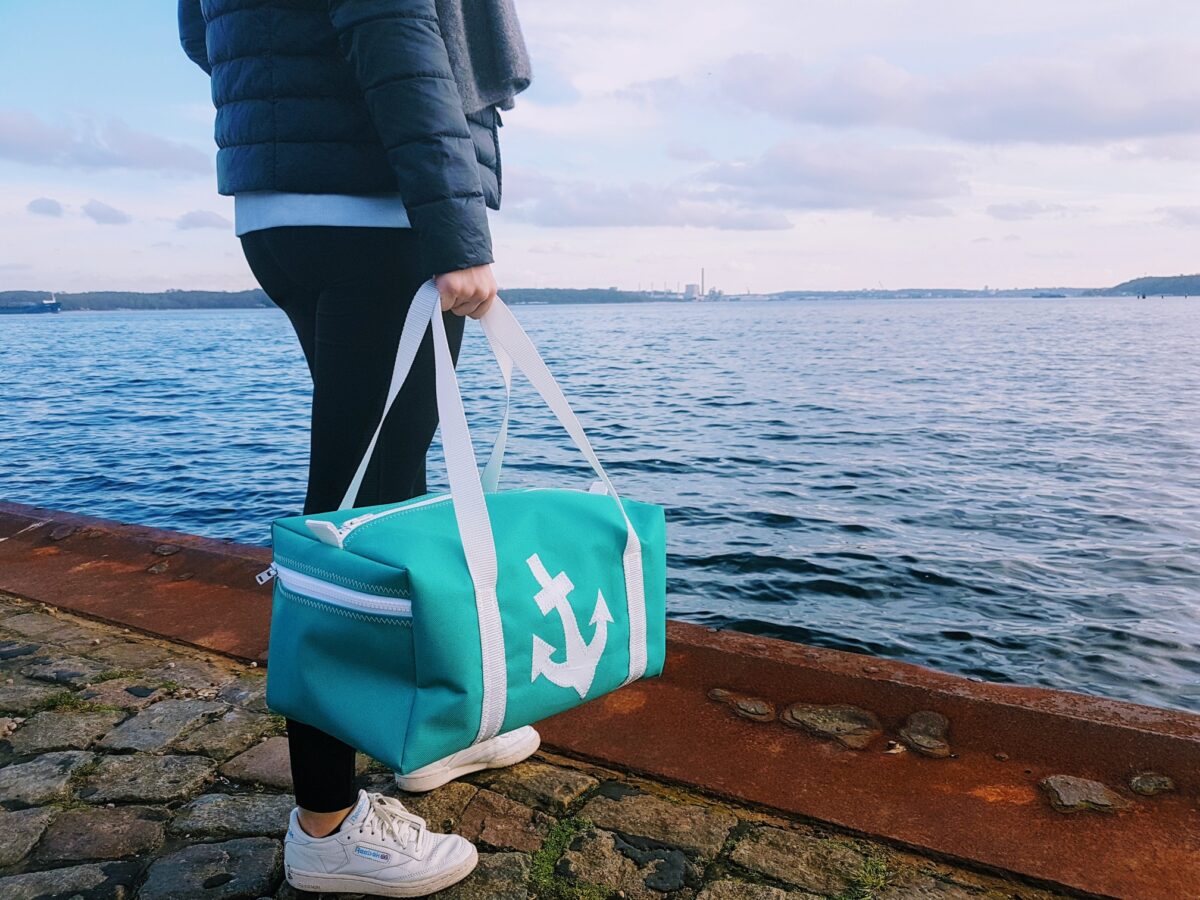 Frau steht auf dem Kai und trägt eine kleine Sporttasche der Größe S in der Hand