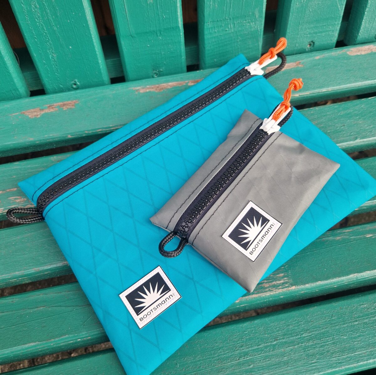 Bootsmann Beutel und Mini Wallet aus X-Pac Segeltuch liegen auf einer alten Holzbank – robust, leicht und wetterfest.