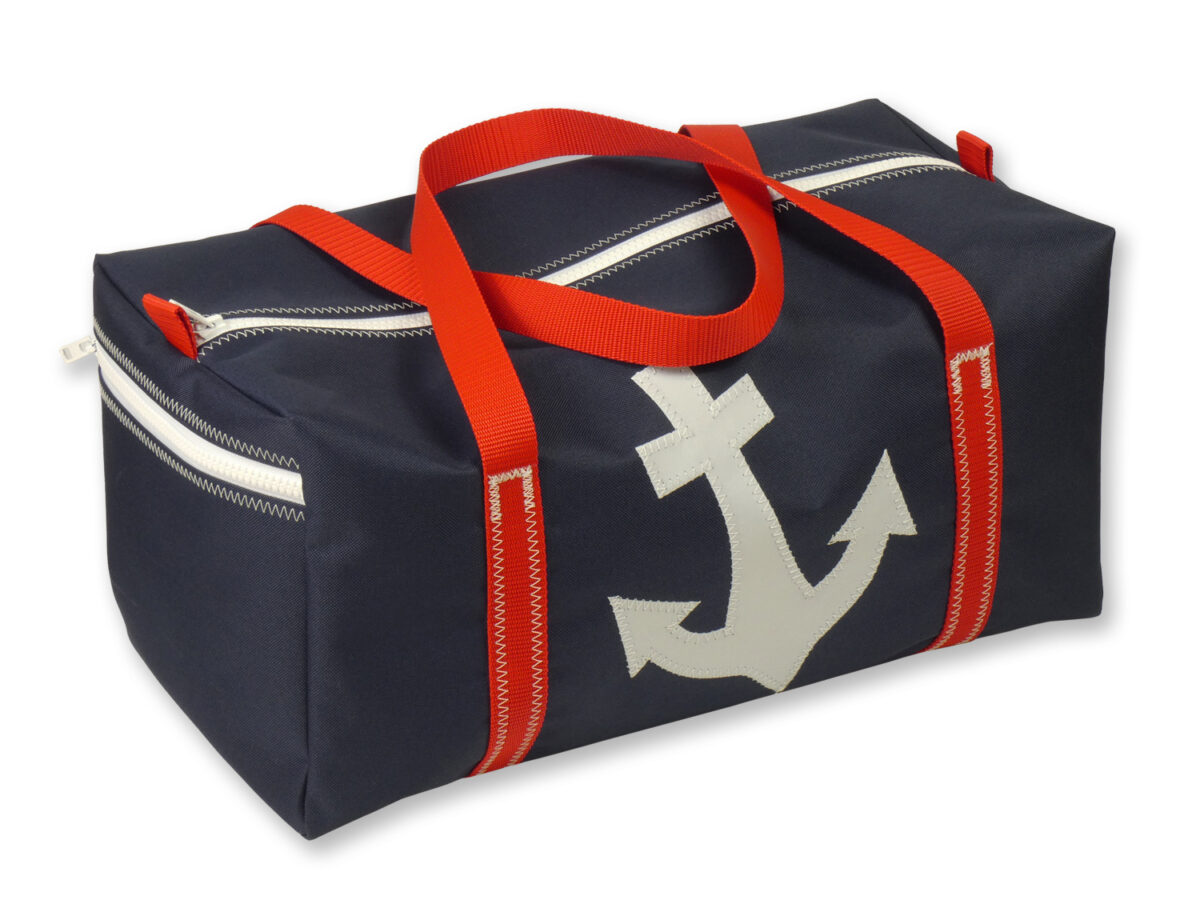 Sporttasche aus Canvas in Größe M. Freigestellt vor weißem Hintergrund. Die Tasche ist navydunkelblau, der Gurt rot, auf der Vorderseite ist ein weisser Anker abgebildet