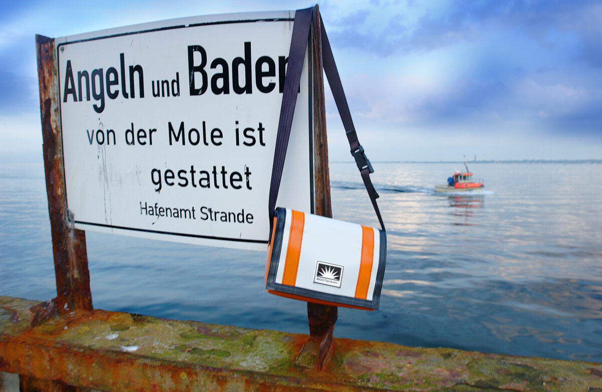 eine Tasche aus LKW-Plane hängt an der Hafenmole